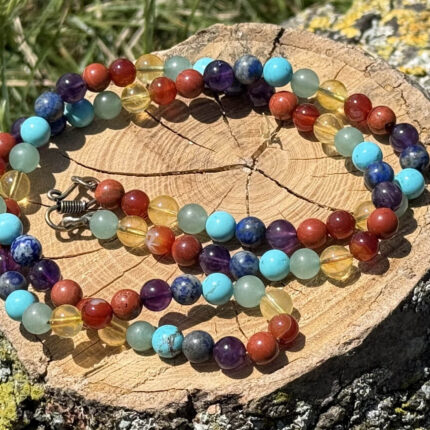 7 Chakra Necklace displayed on a wooden block in a garden with green grass background