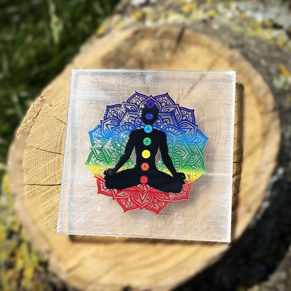 Front view of 7 Chakra Selenite Charging Plate on wooden block with garden grass in background