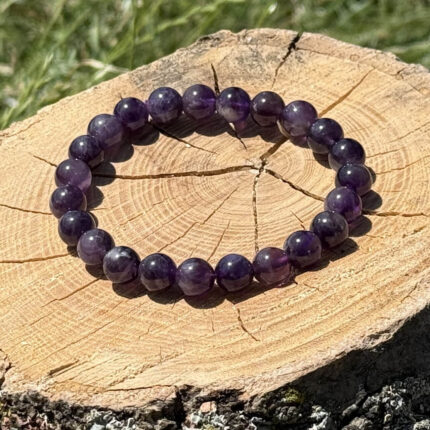 Amethyst crystal bracelet on wooden block with blurred garden background