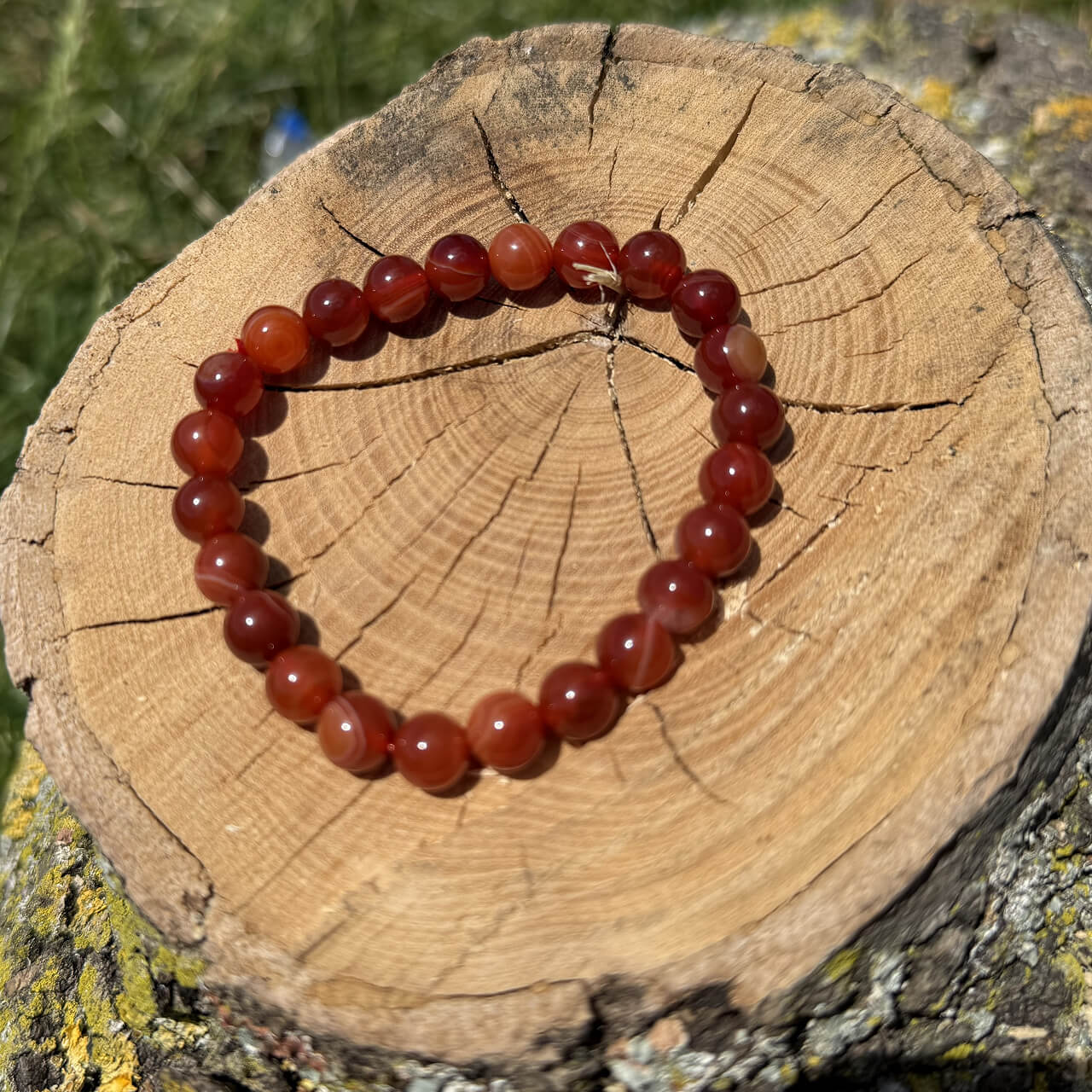 Carnelian crystal bracelet on wooden block with blurred garden background