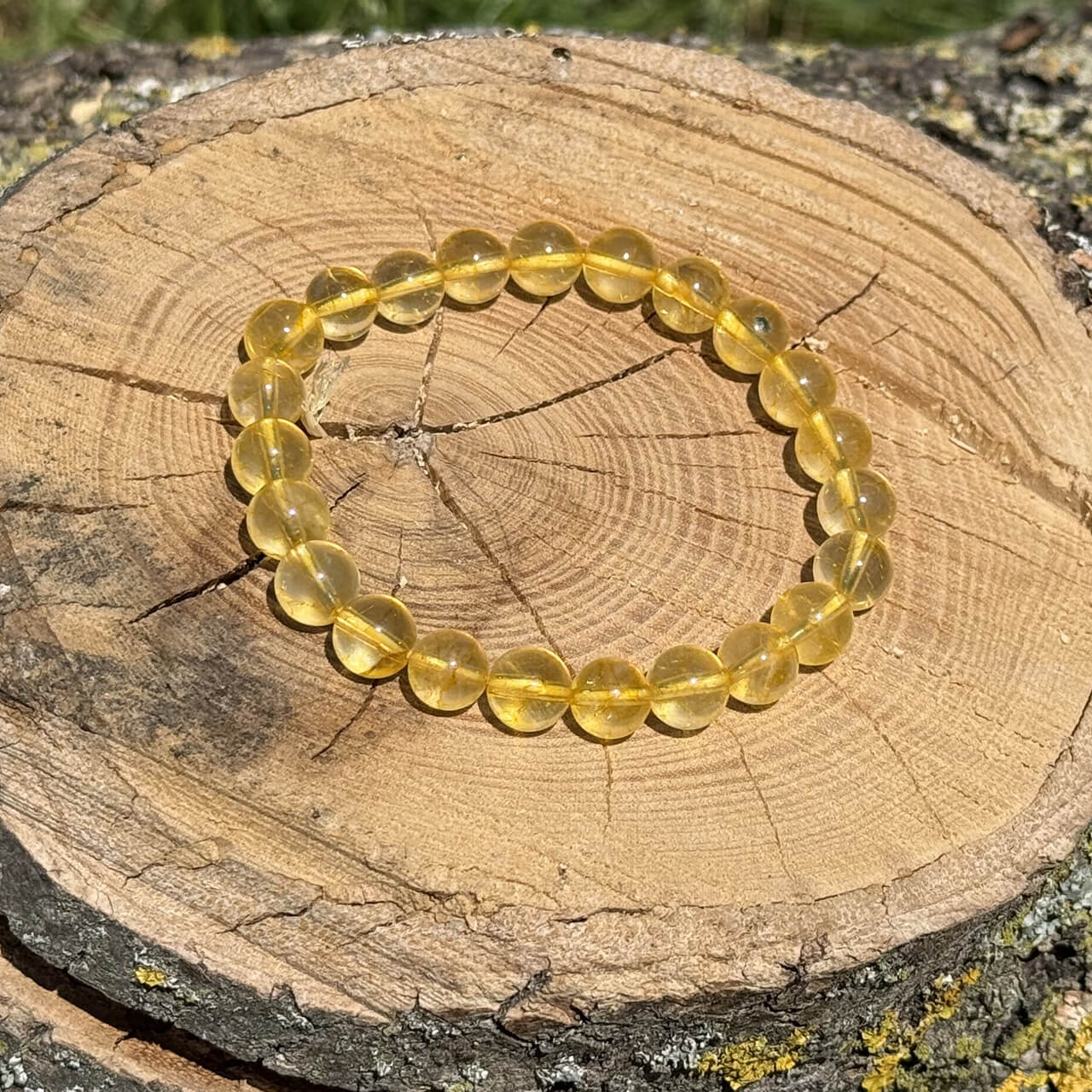 Citrine crystal bracelet on wooden block with blurred garden background
