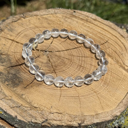 Clear quartz crystal bracelet on wooden block with blurred garden background