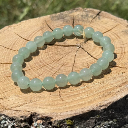 Green aventurine crystal bracelet on wooden block with blurred garden background