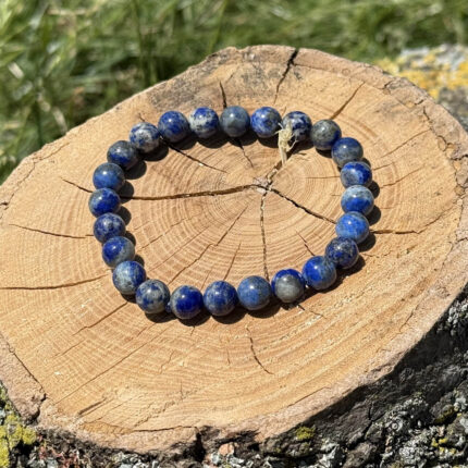 Lapis lazuli crystal bracelet on wooden block with blurred garden background