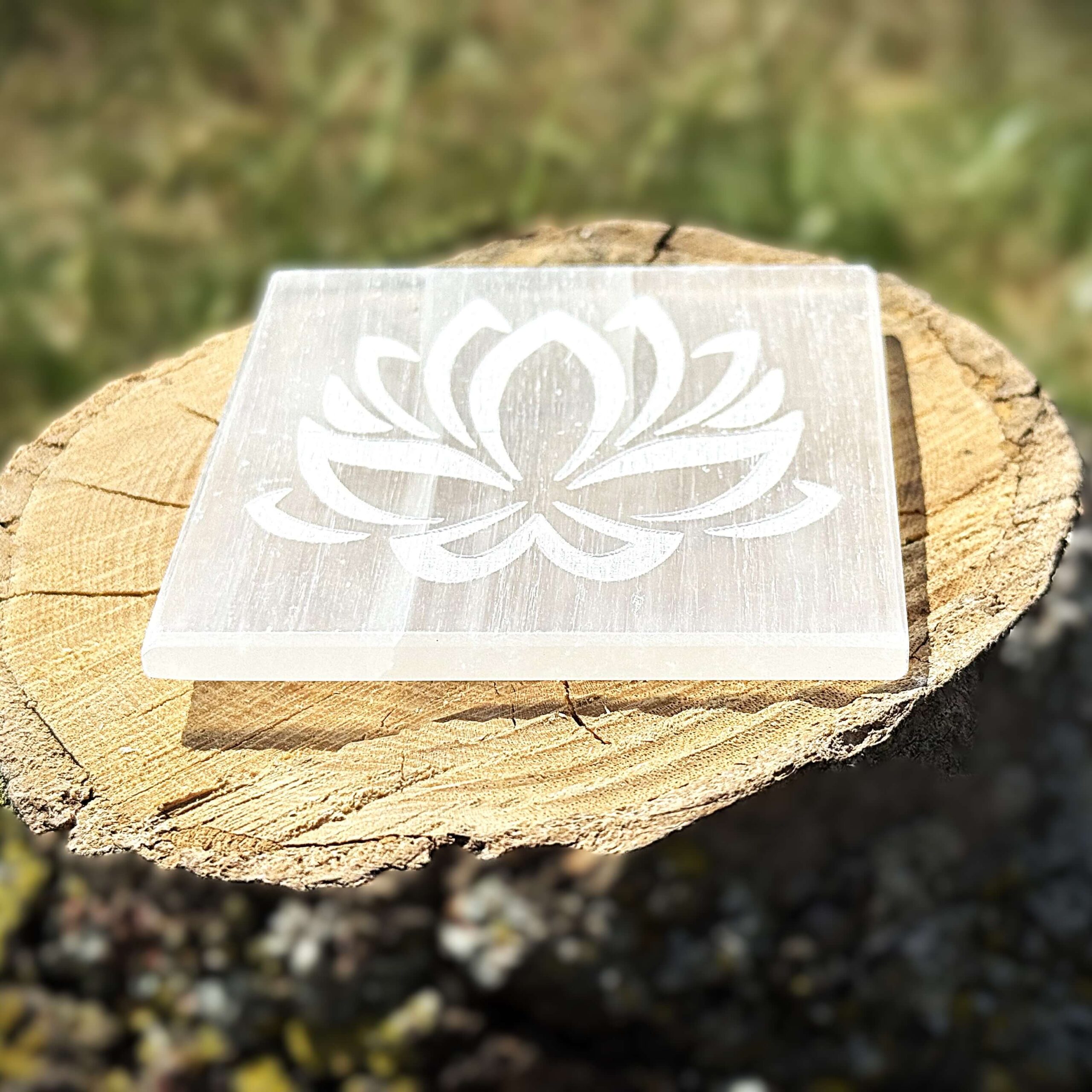 Side view of lotus-engraved Selenite charging plate on wooden block
