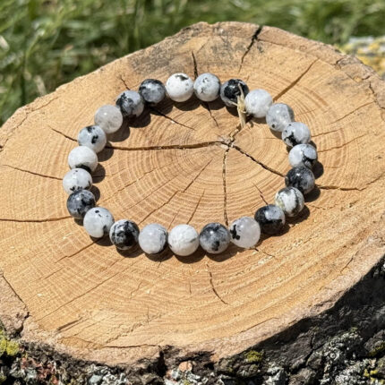 Moonstone crystal bracelet on wooden block with blurred garden background