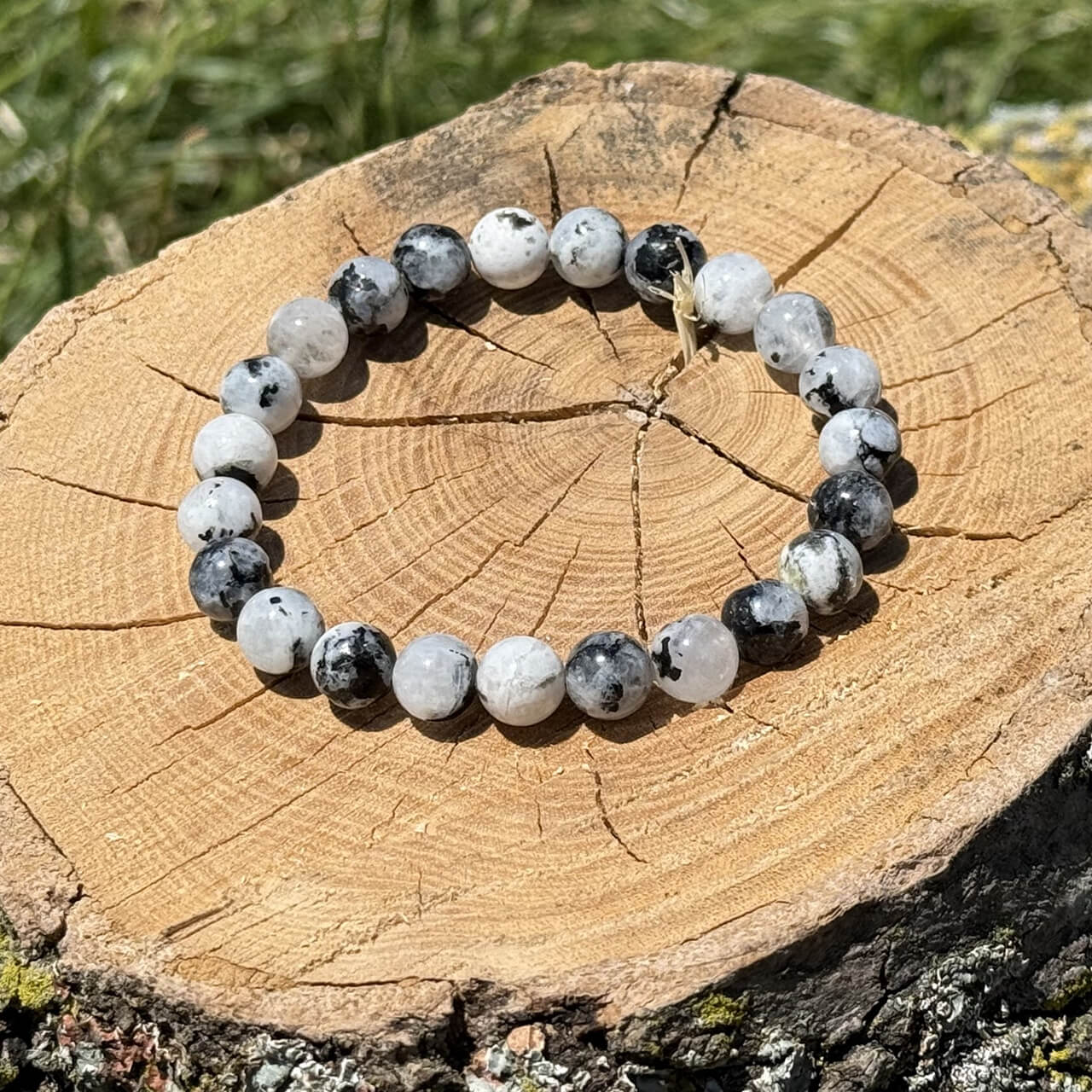 Moonstone crystal bracelet on wooden block with blurred garden background