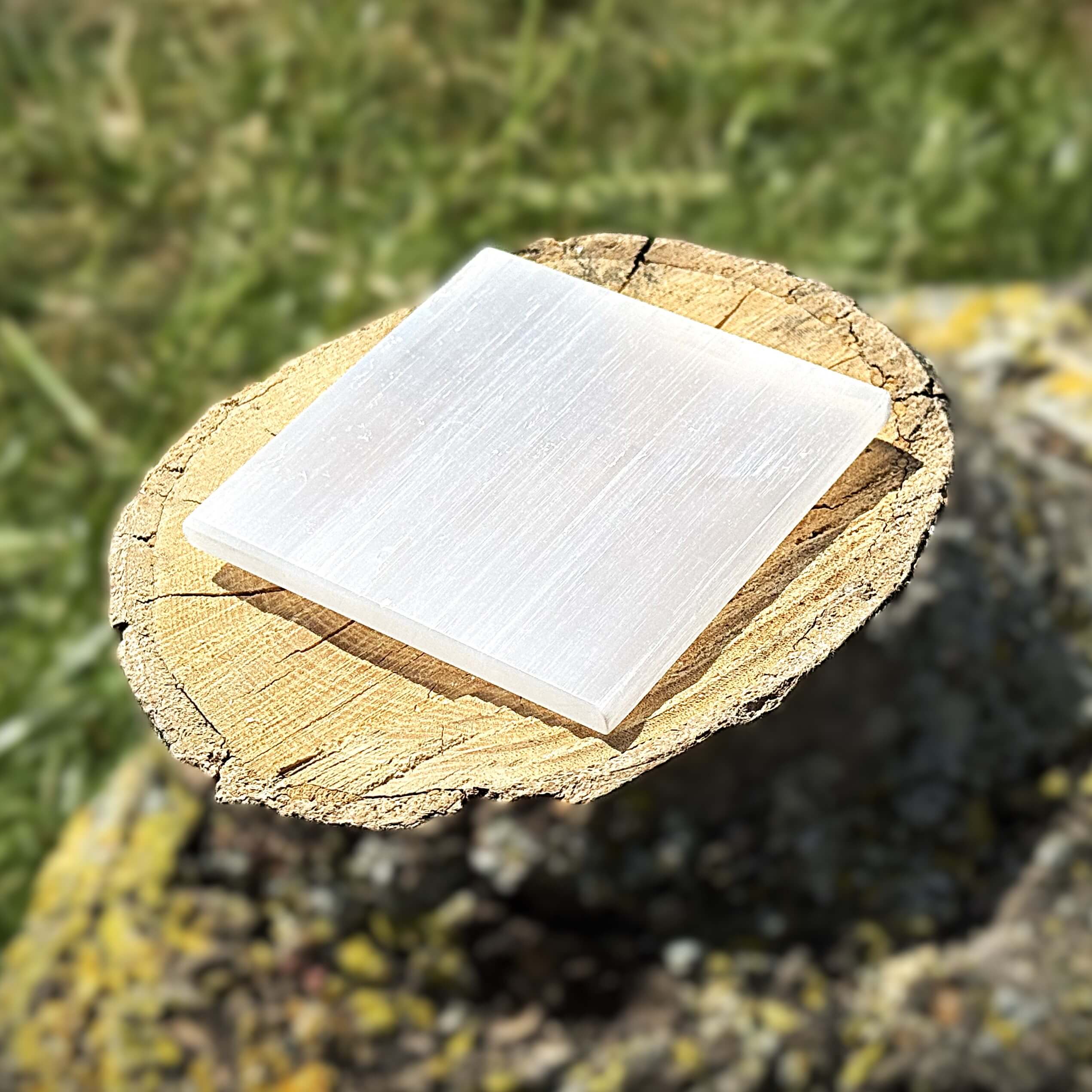 3x3 inch plain Selenite charging plate resting on a wooden surface with a soft natural glow